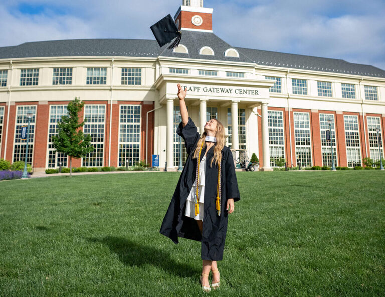 Lycoming College Grad throwing her cap in the air 